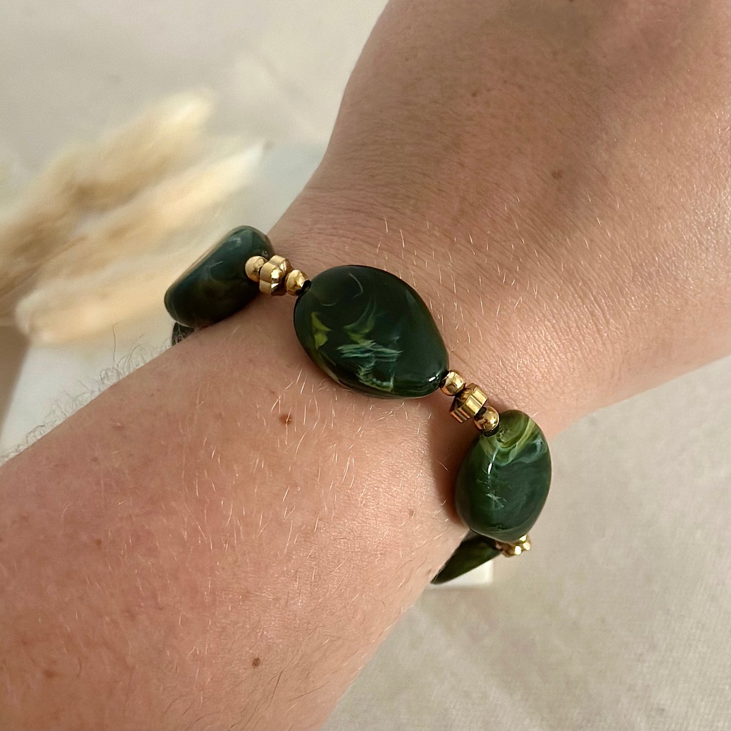 Bracelet élastique doré porté en acier inoxydable pour femme avec perles ovales vertes marbrées prise face - Zoela