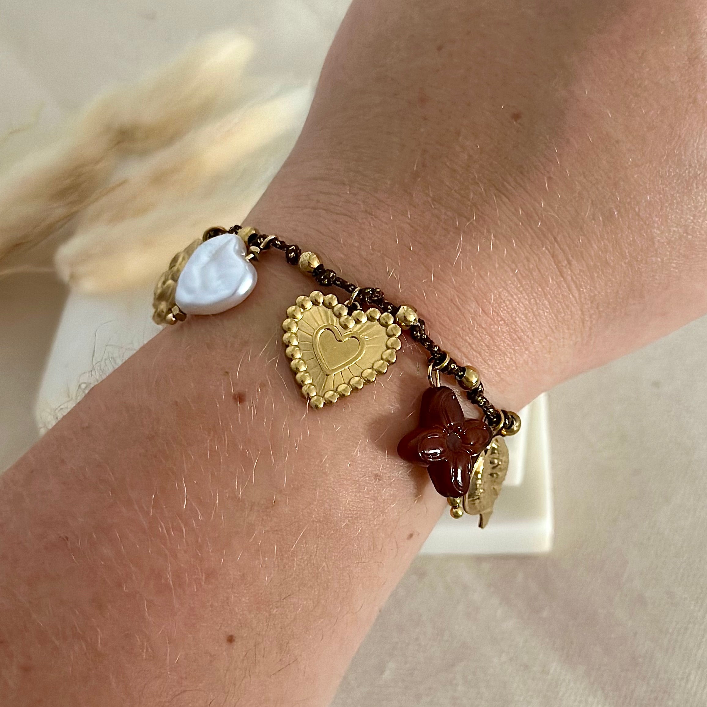 Bracelet doré porté en acier inoxydable pour femme tissu tressé marrons avec charms breloques fleur, coeur, feuille et trèfle prise face - Zoela